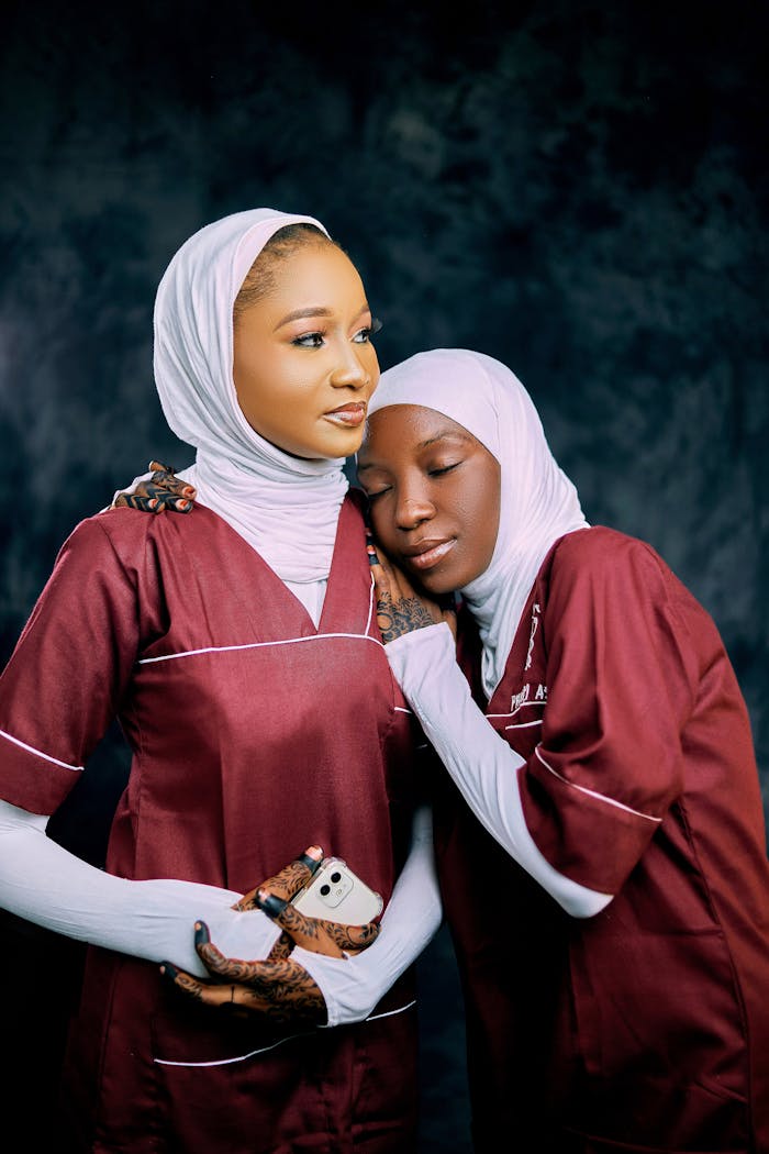 Two female nurses in hijabs share a comforting embrace, reflecting empathy and care.