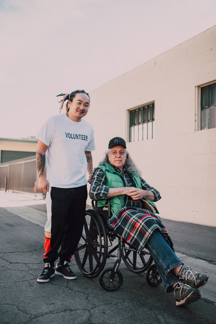 A volunteer helps a person in a wheelchair outdoors, showcasing compassion and support.